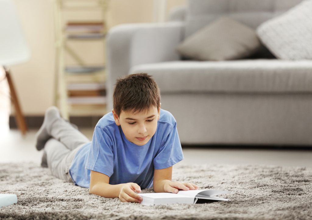 Boy reading on the living room rug.