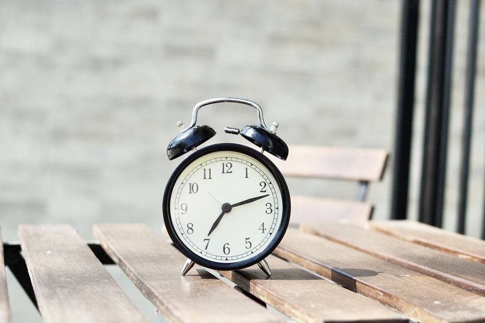 alarm clock on a teak table in broad daylight