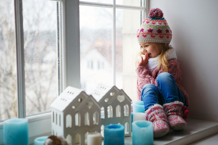 little girl sitting by window in winter
