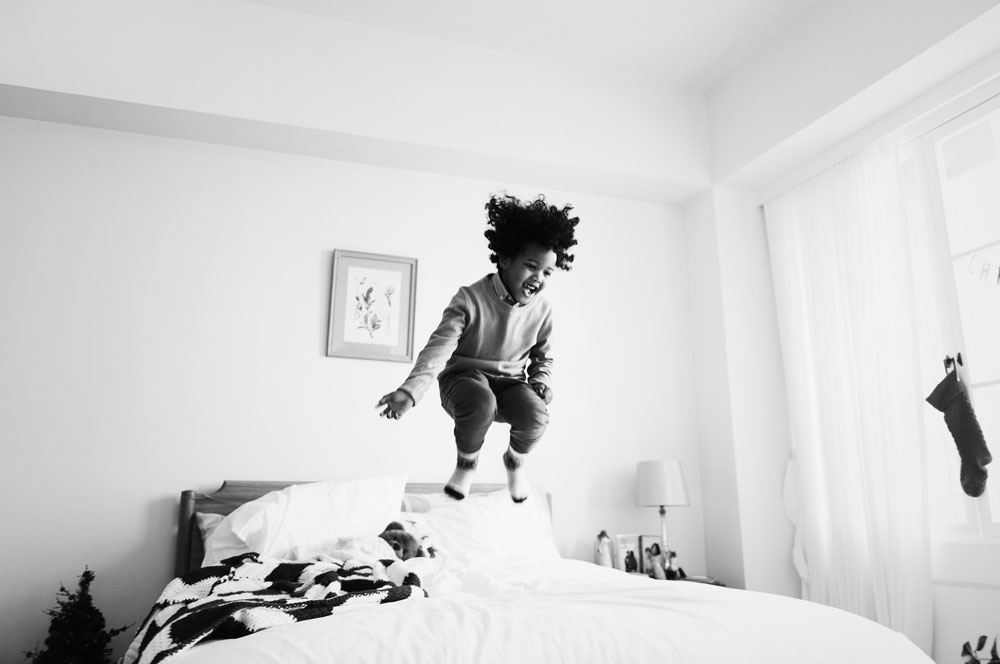 photograph of child jumping on bed