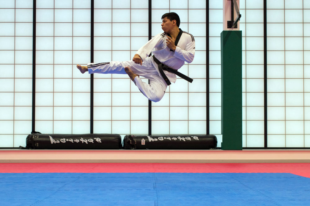 Flying sidekick performed by black belt martial artist in martial arts studio