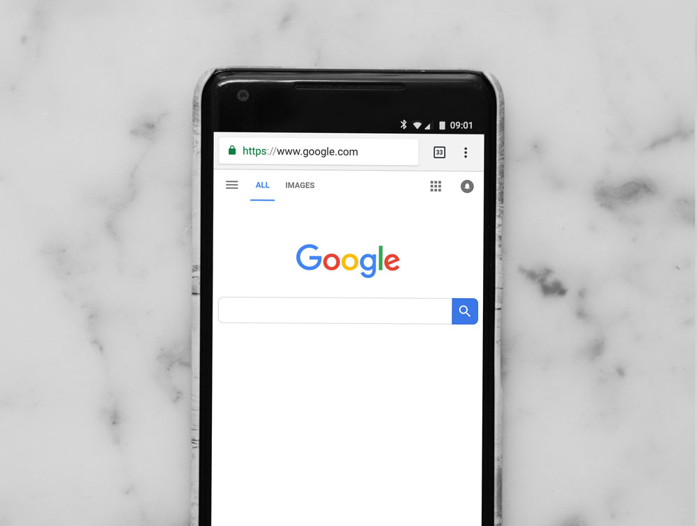 The Google home page on an android mobile phone on a white marble surface